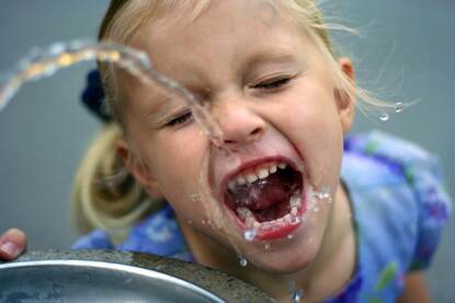 Meisje drinkt van een waterstraal